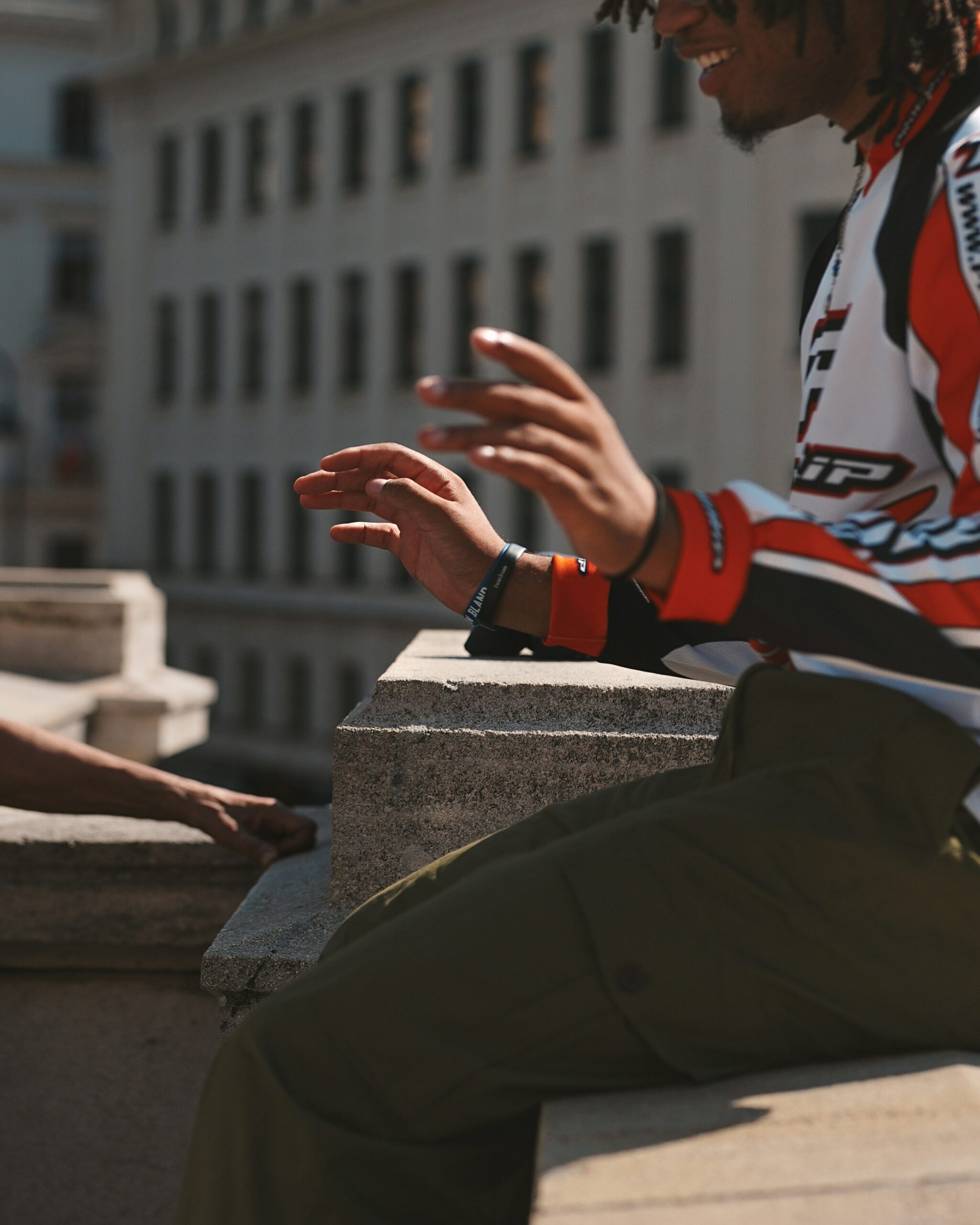 a man with dreadlocks sitting on a ledge